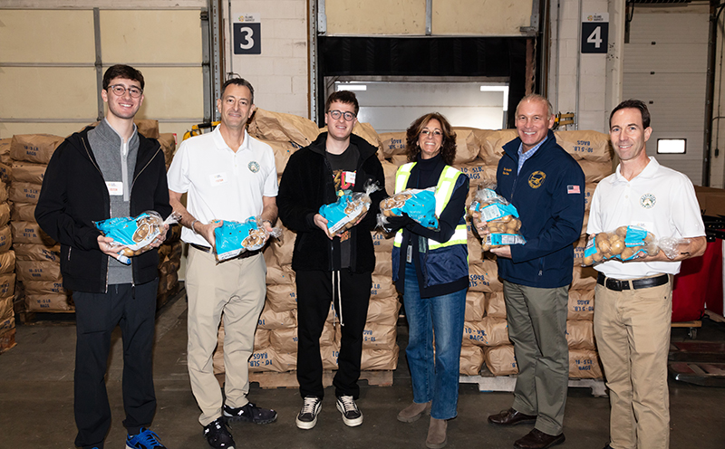 Bushwick Commission executives stand in front of a donation of potatoes destined for the Island Harvest Food Bank, highlighting their contribution of over 18,000 pounds to support local communities.